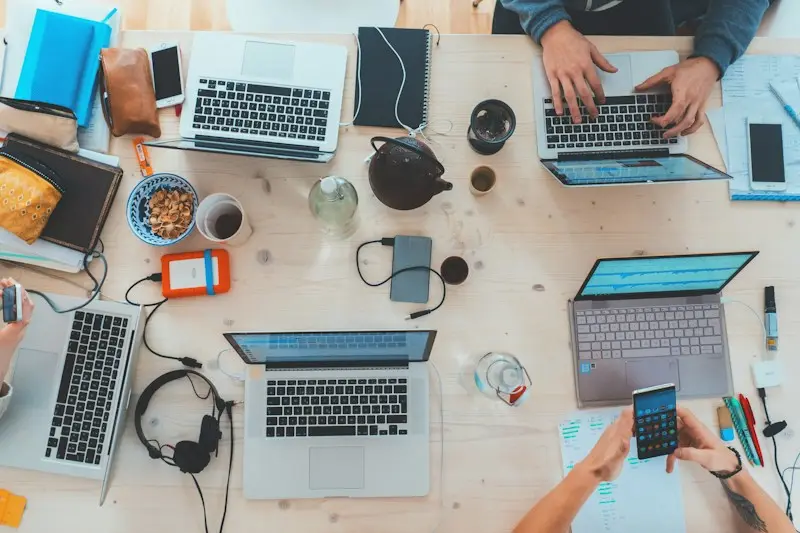 A busy production desk with laptops, notes and phones